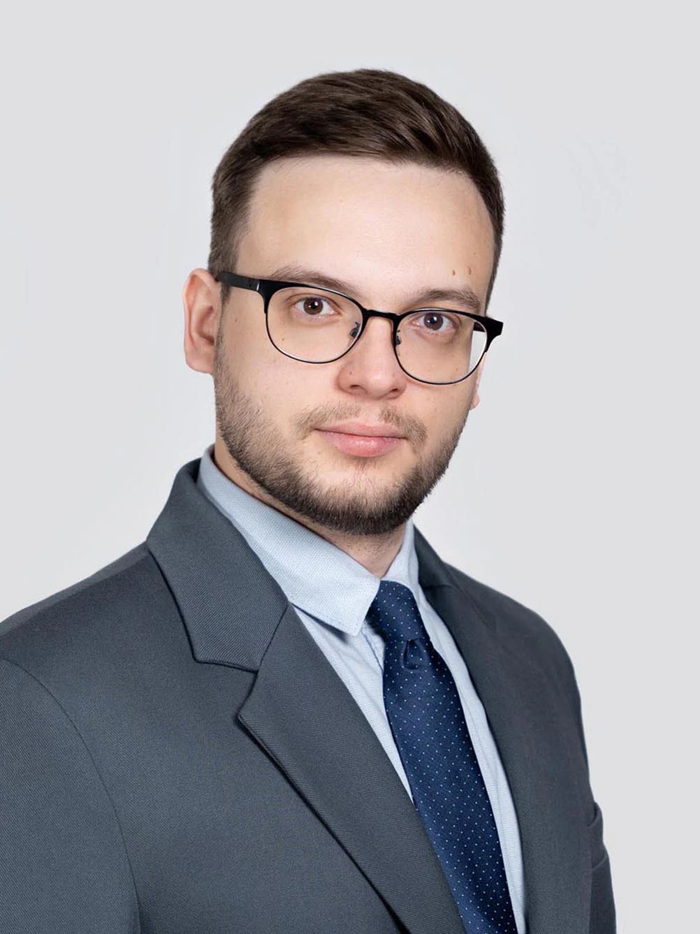 Классический деловой портрет мужчины в очках, сером пиджаке и синем галстуке в крапинку. Студийная бизнес-съемка для резюме в Москве.